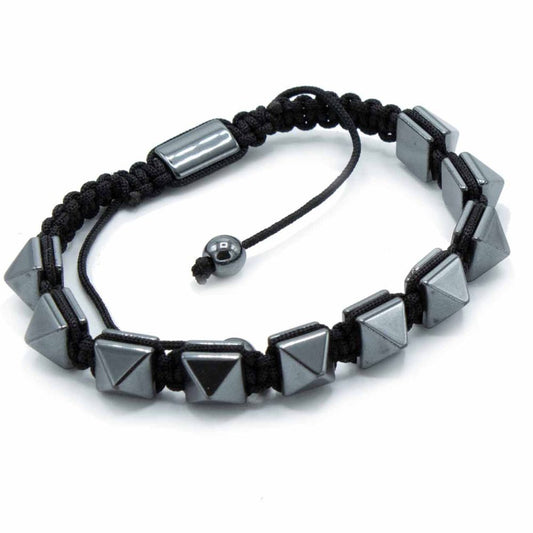 A bracelet is displayed on a white surface; black braided cords connect silver, pyramid-shaped beads. A sliding closure with a small, spherical bead is visible.