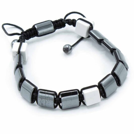 A bracelet lays flat, alternating hematite and white cubes strung on black cord. The bracelet has an adjustable knot closure and rests against a white background.