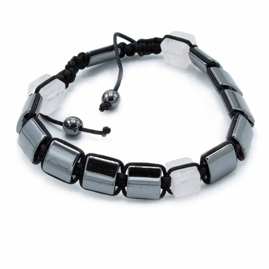 A bracelet, with alternating grey and white rectangular beads held together by black rope, is loosely laid on a white surface. The rope ties are adjustable and end with small grey spherical beads.