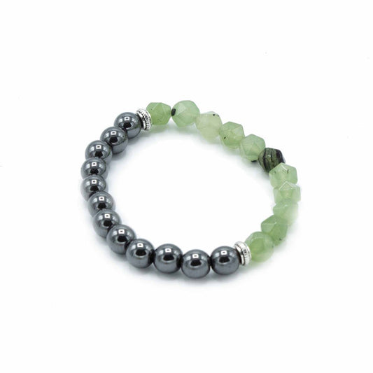 A beaded bracelet curves in the center of a white background. The left side features round, dark gray beads while the right side consists of light green, faceted beads.