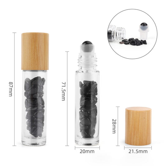 Two glass bottles containing black stones, one with a wooden lid and the other with a rollerball applicator, are measured, set against a plain white background. Text includes: 87mm, 71.5mm, 20mm, 28mm, 21.5mm.