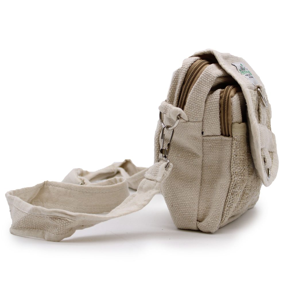 A small, beige hemp bag with silver hardware sits on a white surface. A strap extends from the bag to the left. The bag has multiple zippered compartments.