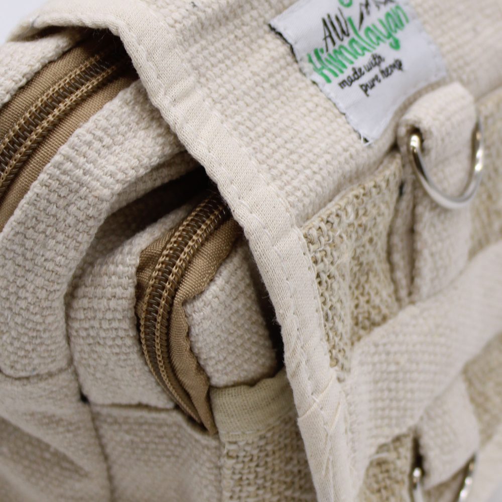 The beige, textured bag with zippers displays a tag that reads "Alu Himalayan, made with pure hemp". It features metal rings.