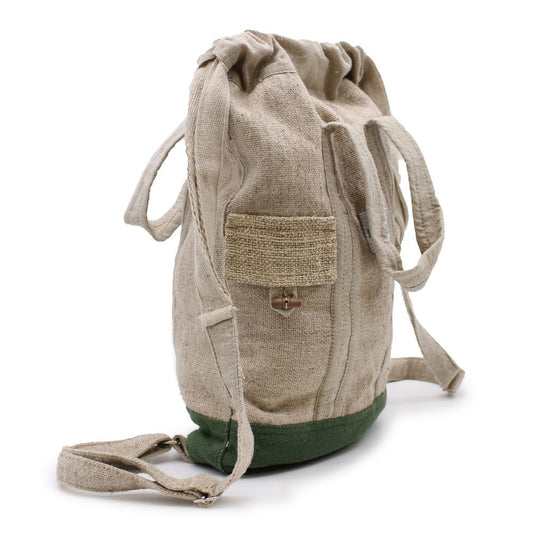 A tan-colored drawstring backpack with green trim stands on a white surface. It features a small woven pocket with a wooden toggle closure.
