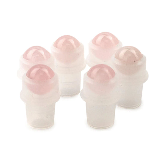 Six semi-translucent bottles with pink, rounded roller ball tops sit against a bright white background. The bottles are arranged closely together, with the tops rounded.