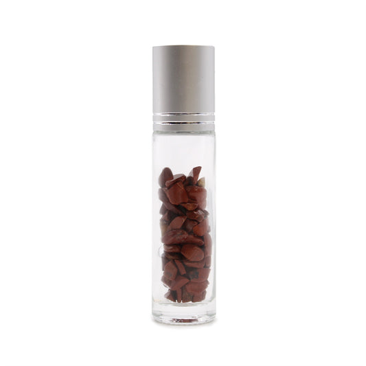 A clear glass roller bottle with a silver cap is filled with small, polished, red-brown stones against a plain white background.