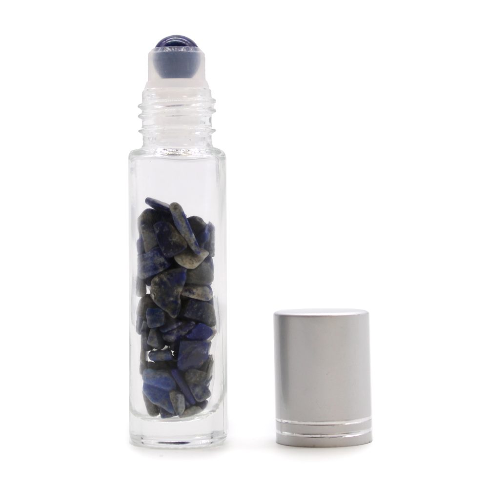 A glass roller bottle, containing blue lapis lazuli stones, rests on a white background; its silver cap is shown separately.