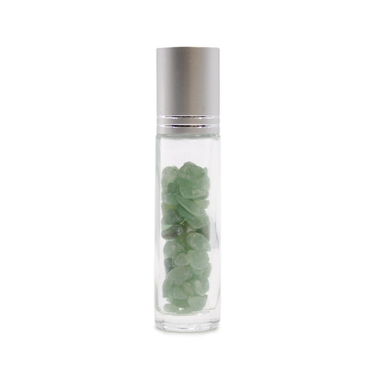 A clear, glass rollerball bottle with a silver cap sits upright, showcasing small, pale green gemstones filling the center. The background is plain white.