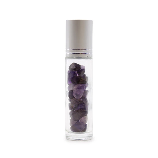 A clear, slender roller bottle is filled with small, dark purple gemstones. The bottle has a metallic cap and sits on a white surface.