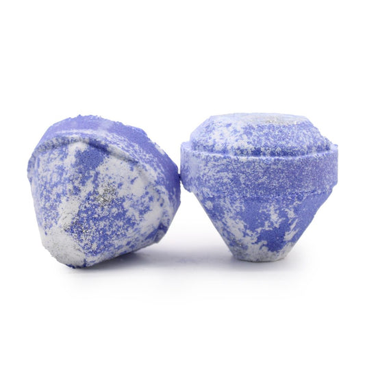 Two textured, purple and white bath bombs rest on a smooth white surface, appearing as multifaceted geometric shapes, suggesting a spa or relaxation context.