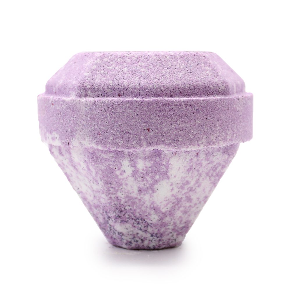 A purple, textured bath bomb with a geometric, faceted shape rests on a white surface, displaying a mix of light and dark purple hues throughout.