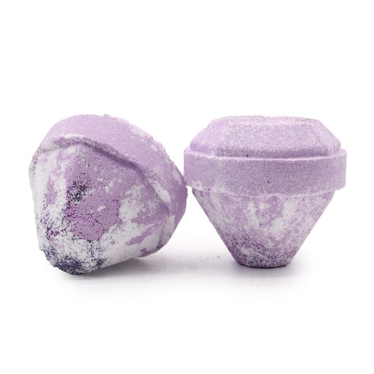 Two purple bath bombs sit side by side, showcasing a textured surface with white and darker purple patches, against a plain white background.