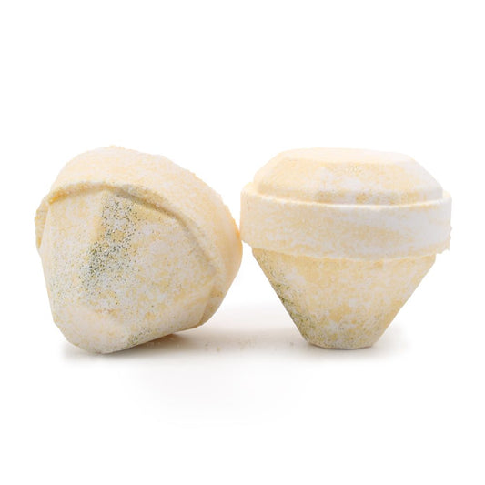 Two yellow bath bombs rest side by side, featuring a diamond-like shape with a dusting of white, set against a plain white background.