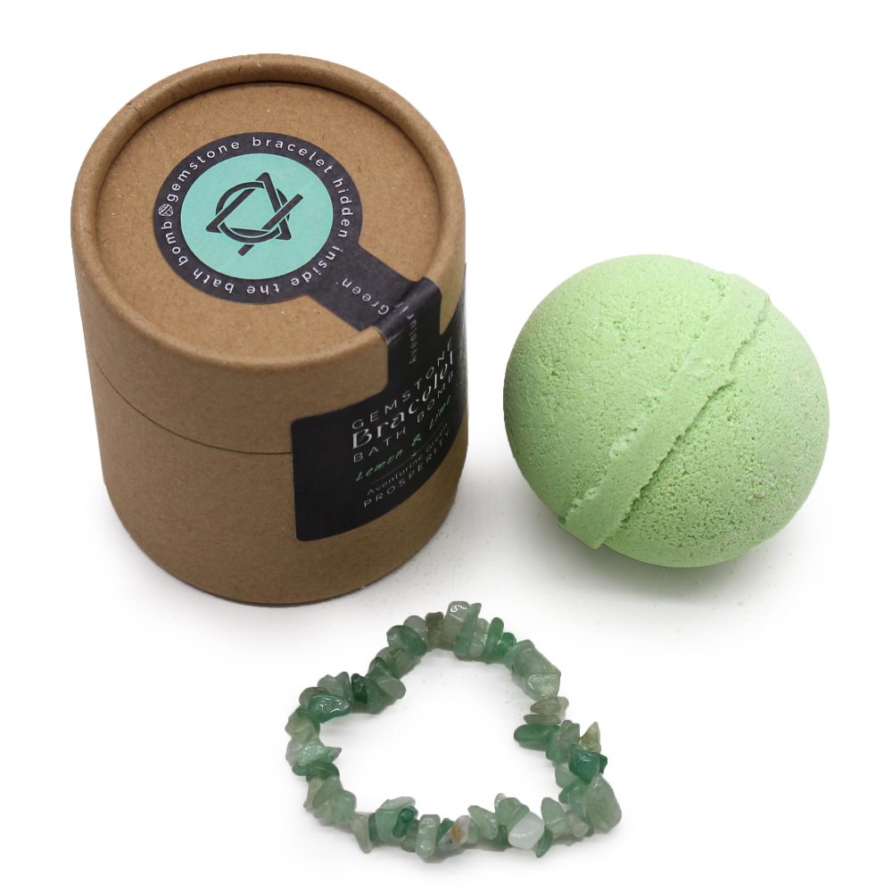 A green bath bomb, a cardboard container, and a green gemstone bracelet are displayed on a white surface. The container reads "Gemstone Bracelet Hidden Inside the Bath Bomb."