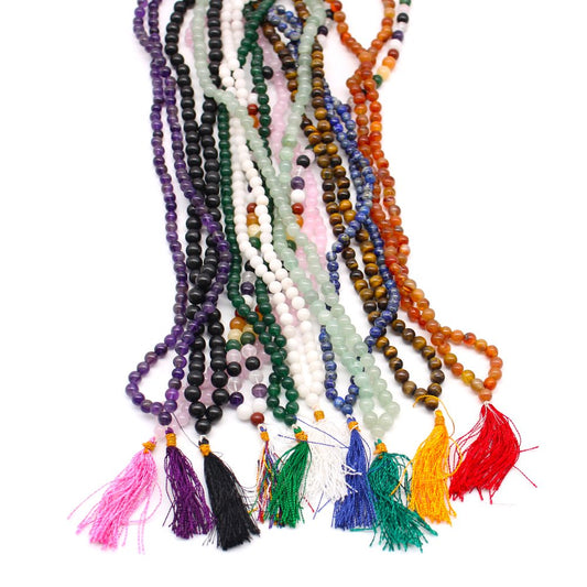 Several colorful beaded necklaces with tassels hang vertically against a white background.