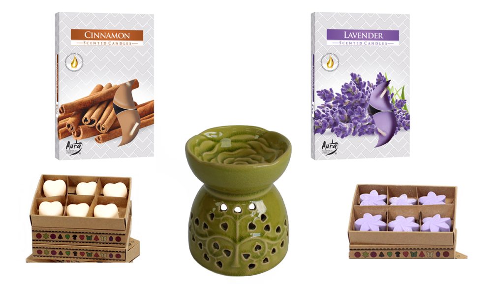 A green ceramic oil burner sits centrally. Flanking it are boxes of cinnamon and lavender scented candles, plus matching wax melts in heart and flower shapes.