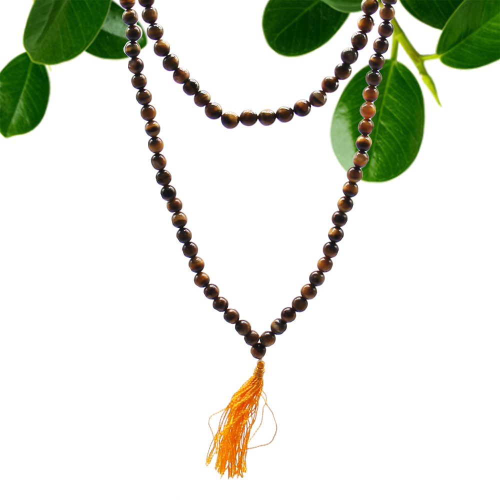 A brown beaded necklace with a tassel hangs against a white background. Green leaves are in the top corners.