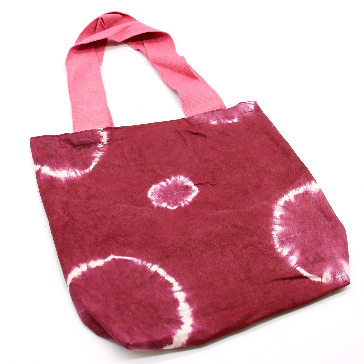A maroon tie-dye tote bag with pink straps sits on a white surface. The bag is slightly angled to the right.