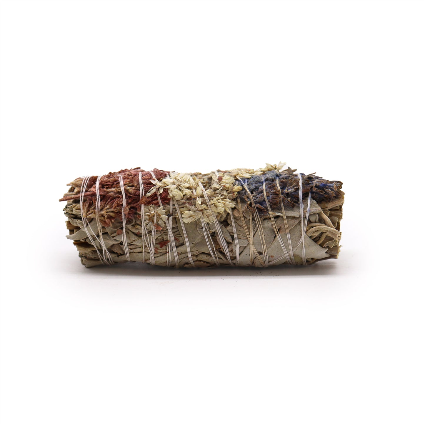 A smudge stick, bound with twine, rests on a white background. It contains dried herbs in red, white, and purple hues.