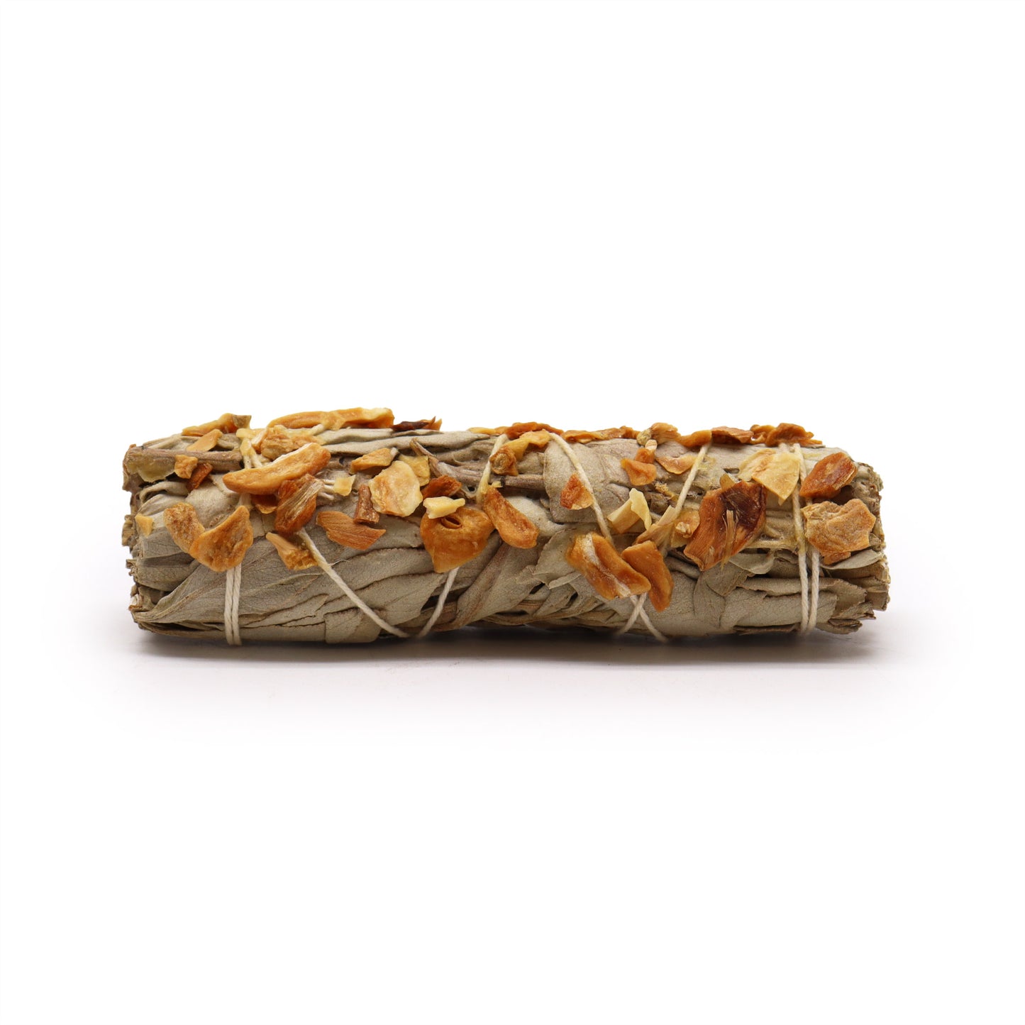 A sage smudge stick, bound with twine and studded with dried garlic pieces, rests on a plain white background.