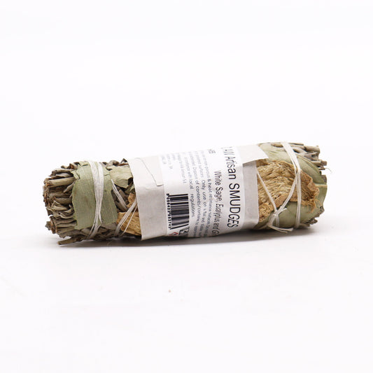 A smudge stick, bundled and tied, rests on a white surface. The label reads: "AW Artisan SMUDGES, White Sage, Eucalyptus and Ginseng." Additional instructions for use and disposal are included.