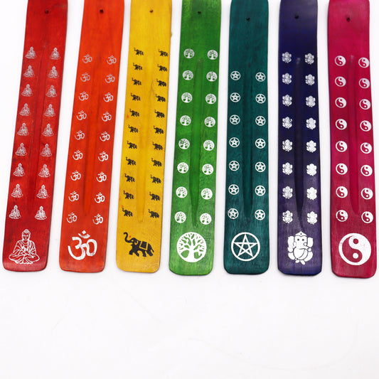 Wooden incense holders display symbols like Buddha, Om, elephants, trees, pentagrams, and Yin-Yang. Each holder has a distinct color: red, orange, yellow, green, blue, or purple.