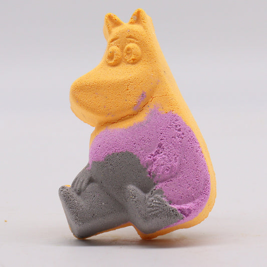 A colorful bath bomb shaped like a cartoon character features shades of yellow, purple, and gray, sitting upright against a plain, light background.