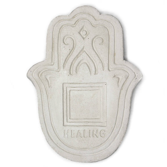 The object is a stone plaque shaped like a hamsa, featuring engraved decorative patterns and the word "HEALING" at the bottom, set against a plain background.