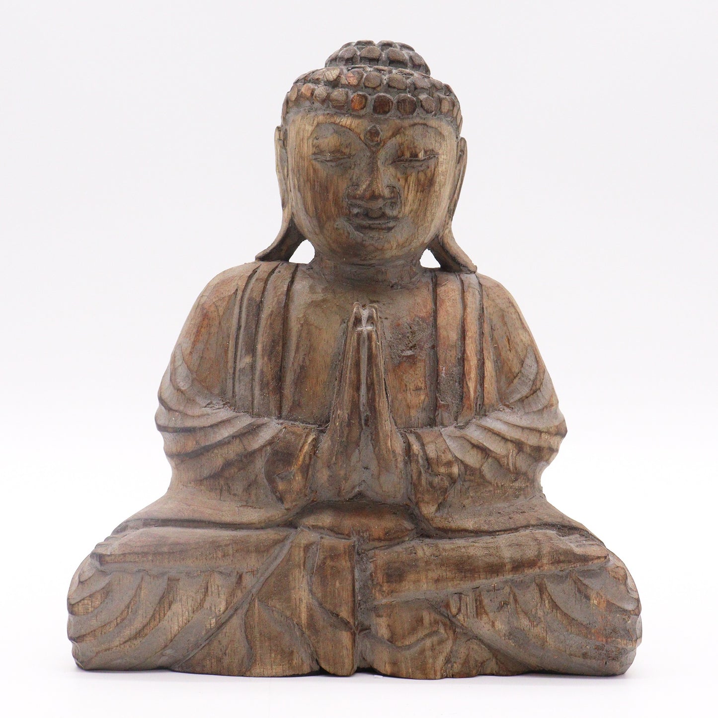 A wooden Buddha statue sits cross-legged with hands in prayer position, featuring detailed robes and a serene expression, set against a plain white background.