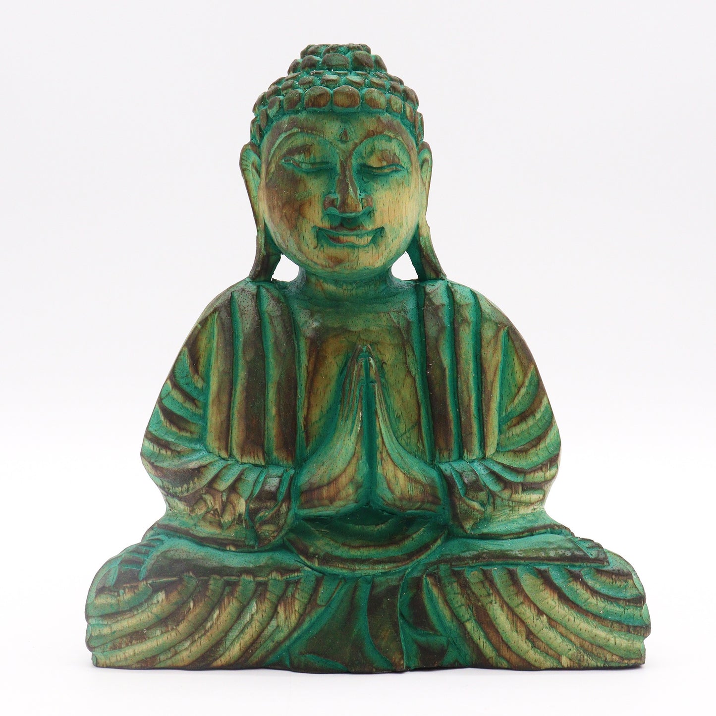 A wooden Buddha statue sits with hands in a prayer gesture, featuring detailed carvings and a weathered green patina against a plain white background.