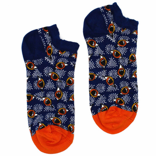 A pair of ankle socks, patterned with stylized eyes and geometric shapes on a dark blue background, rests on a white surface.