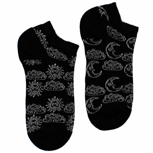 A pair of black ankle socks displays a pattern of suns, moons, and clouds. The pattern is embroidered in silver thread. They are presented against a white background.