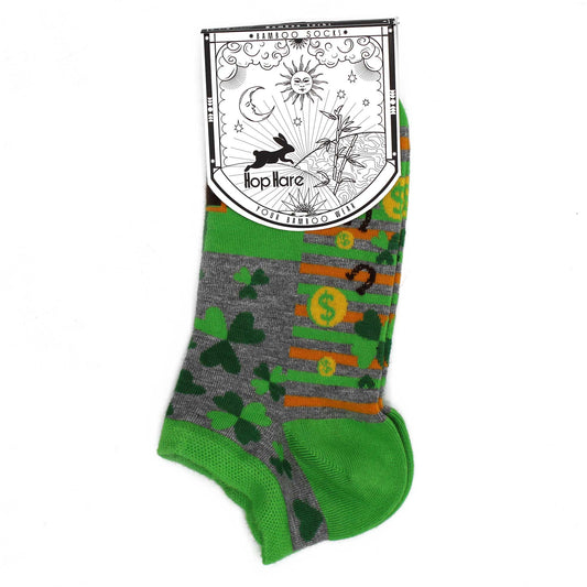 A pair of ankle socks displays a pattern of shamrocks, dollar signs, and orange stripes on a grey background. The socks are attached to a card that reads: *BAMBOO SOCKS*, Hop Hare, YOUR BAMBOO WEAR.