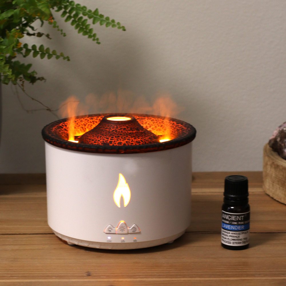 A white diffuser emits orange, flame-like light and vapor from a dark, textured cone-shaped top. Next to the diffuser sits a bottle labeled “ANCIENT / 10ML PURE ESSENTIAL / LAVENDER”.