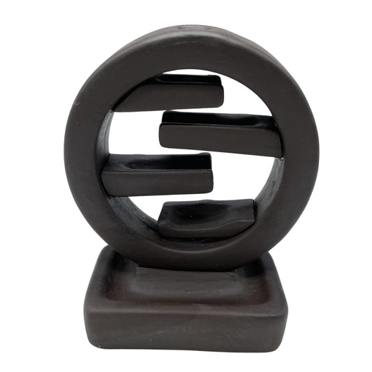 A dark brown ceramic sculpture features an abstract circle with three horizontal bars inside, resting on a square base, against a plain white background.