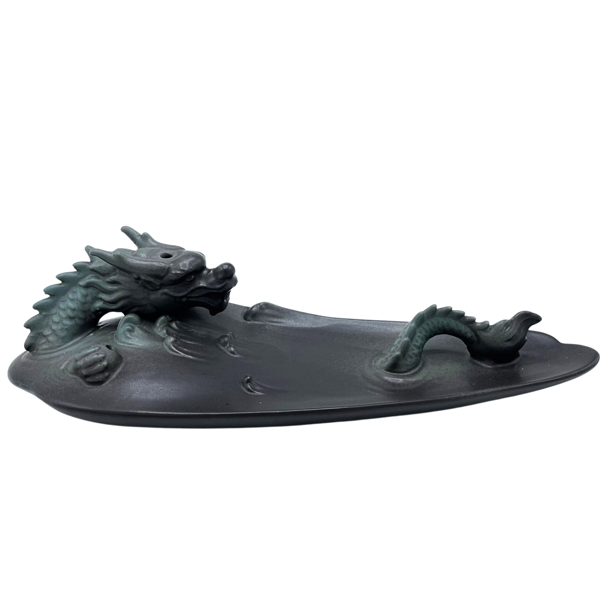 A black, intricately detailed dragon figurine rests on a flat surface, with its head emerging from one end and its tail from another, suggesting a swimming motion.