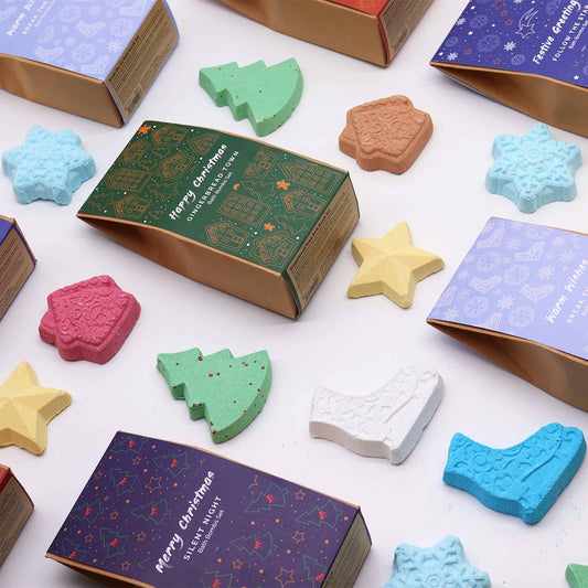 Boxes with Christmas-themed bath bombs, featuring shapes like trees, stars, and snowflakes, are scattered on a surface. Text includes "Merry Christmas" and "Happy Christmas" on decorated packaging.