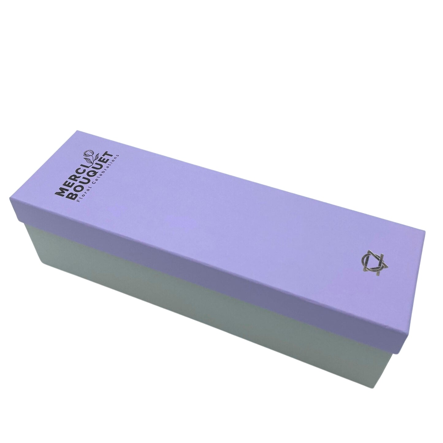 A lavender-colored box, with a light green base, rests on a white background. The top displays “MERCI BOUQUET Floral Celebrations” and a logo.