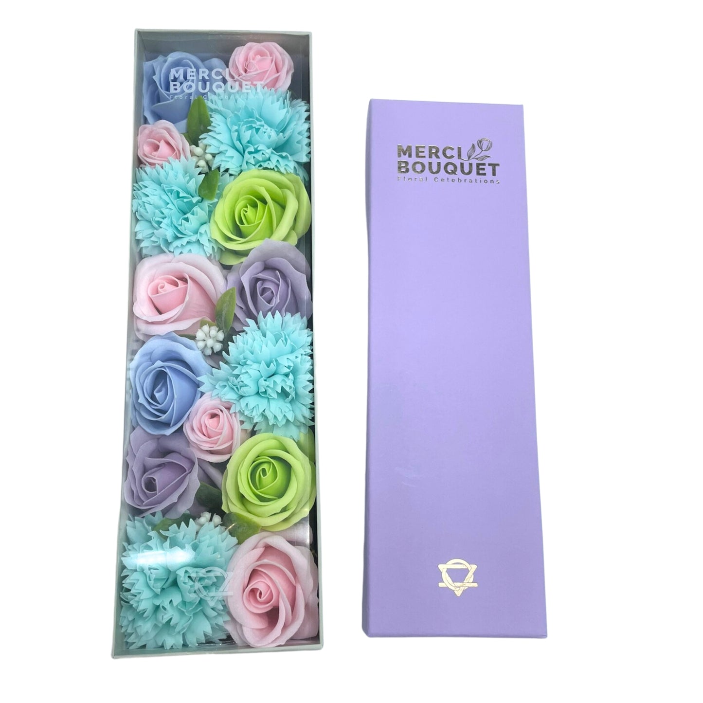 Pastel soap roses and carnations are arranged in a clear box; next to it sits a lavender box. The boxes are labeled "MERCI BOUQUET Floral Celebrations".