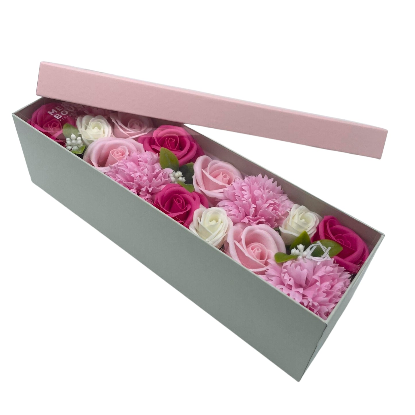 A light-green box contains an arrangement of pink, white, and fuchsia soap flowers; its light-pink lid is ajar. MERI BOUQUET is visible on the box's interior.