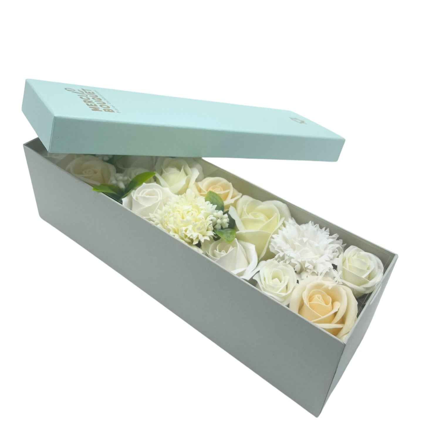 A pale-green box containing a bouquet of soap roses and carnations in various shades of white and cream, sits slightly angled against a white background. The lid is ajar. The box is labeled "Merciel Bouquet."