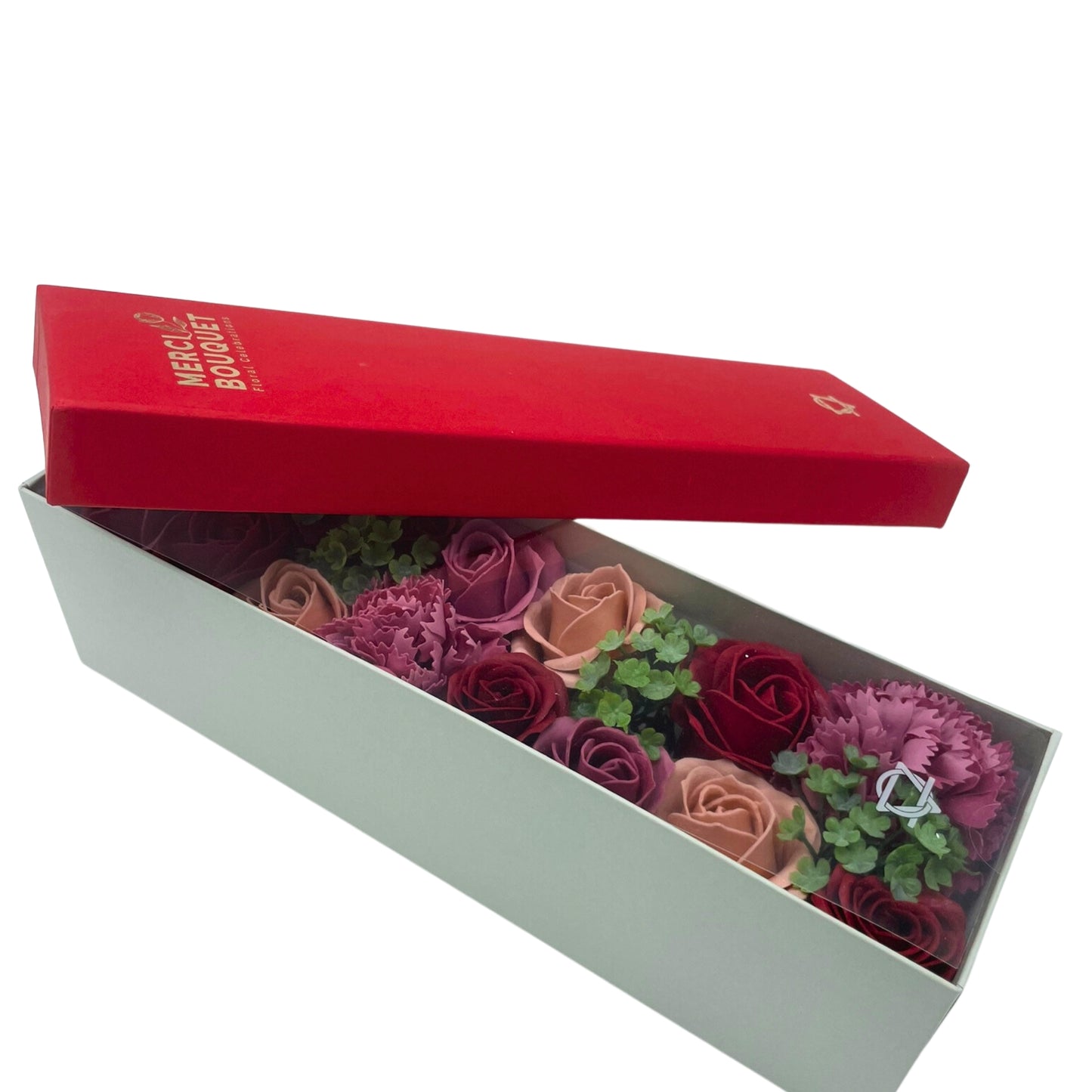 A pale green box contains a bouquet of red, pink, and burgundy roses and carnations. The box is partially covered by its bright red lid, which reads: MERCI BOUQUET Floral Creation.