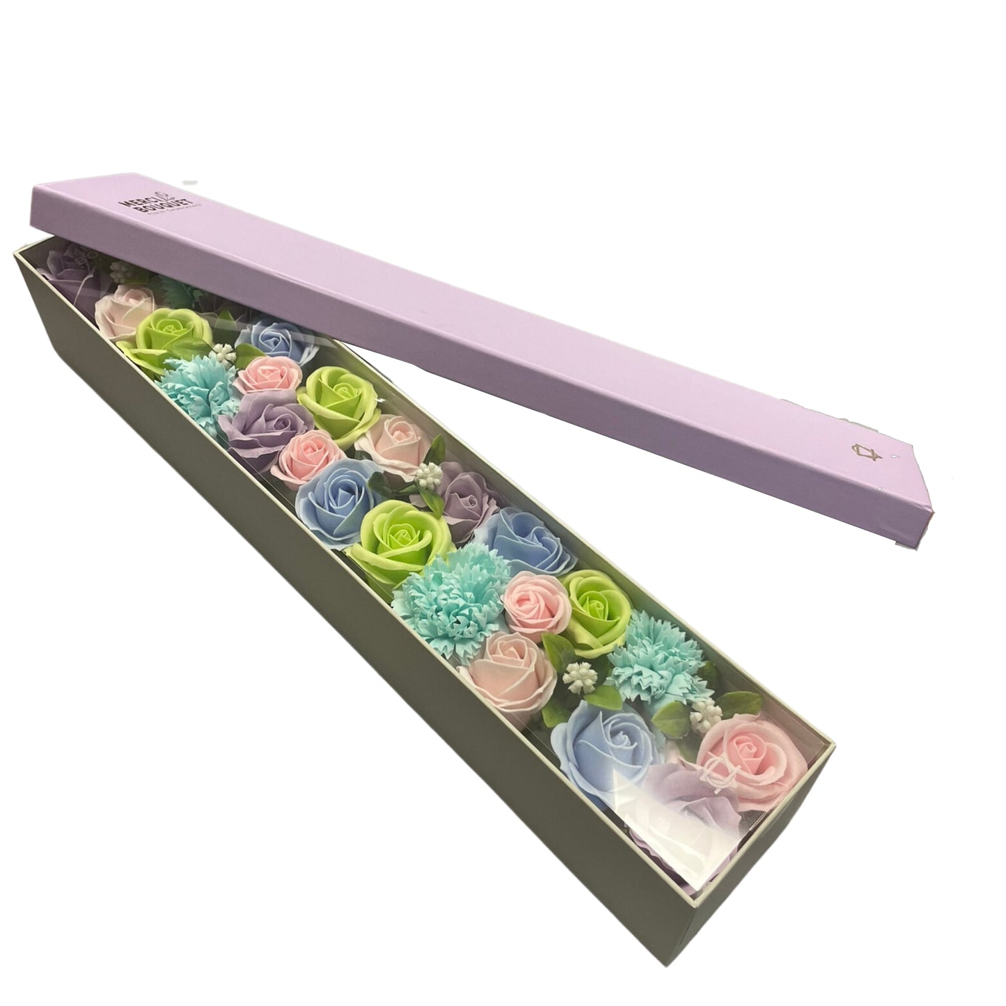 A pastel soap flower bouquet rests in a light gray box, its lid, a pale purple, is ajar. The box is rectangular and long. The lid displays the text: "MERCI BOUQUET Soap Flowers."