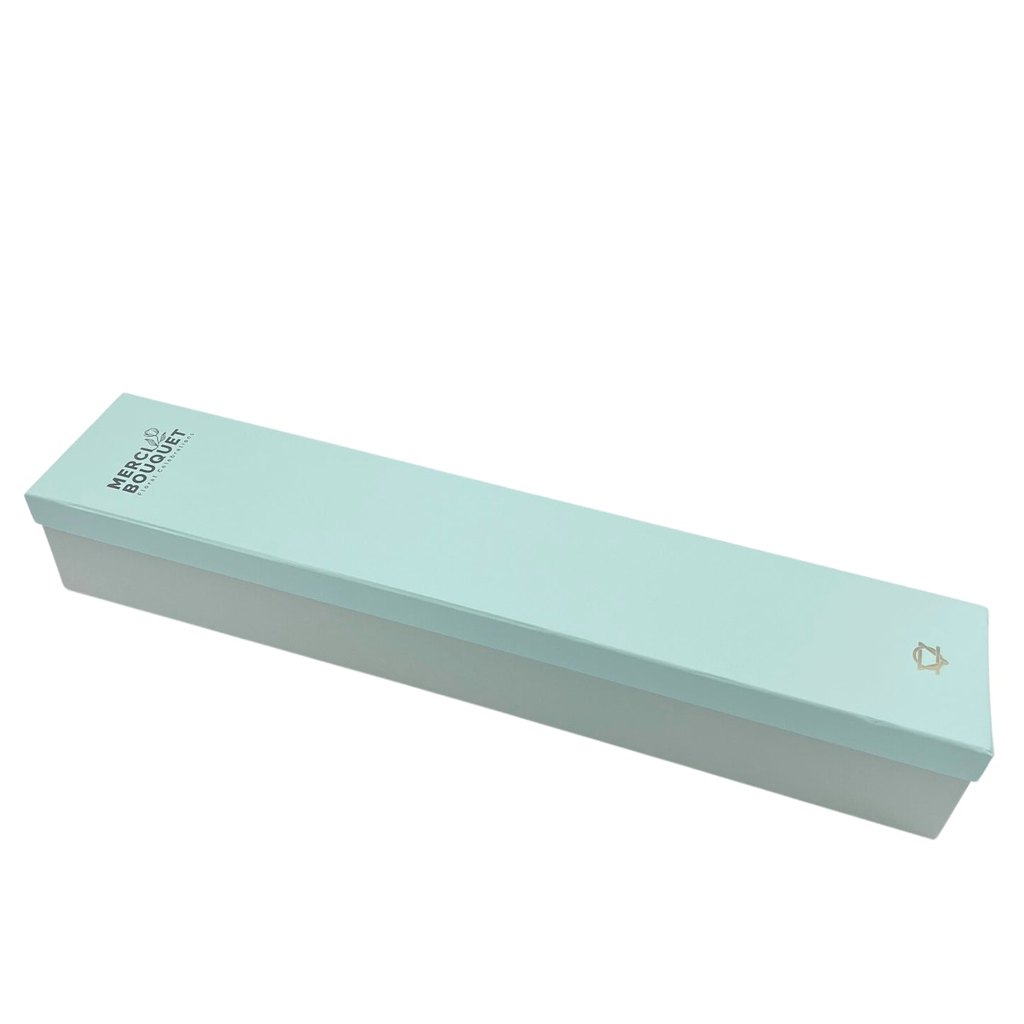 A light teal rectangular box rests on a white background. The box is labeled "MERCI BOUQUET Floral Creations." A small logo is present on the bottom right.