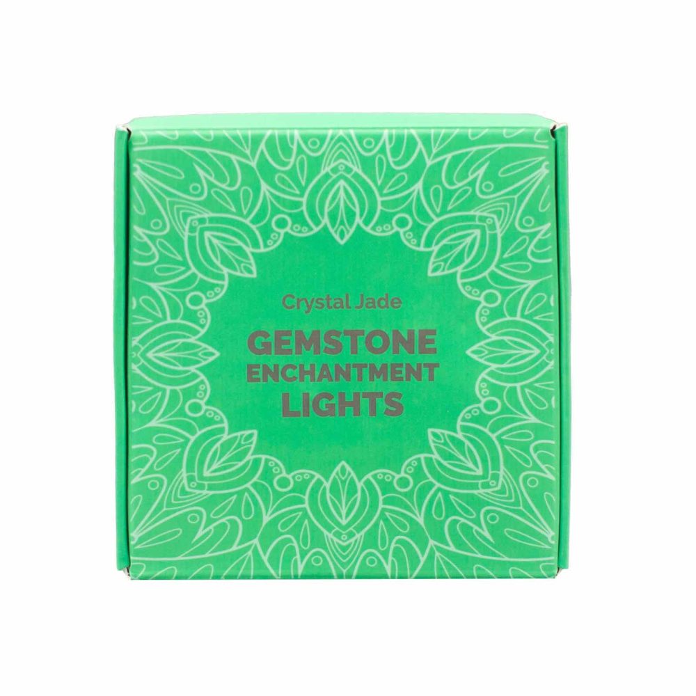 A green box displays the text "Crystal Jade GEMSTONE ENCHANTMENT LIGHTS" in white font, framed by stylized leafy patterns in a lighter shade of green. It is isolated against a white background.