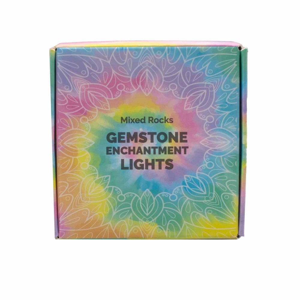 A square box labeled "Mixed Rocks GEMSTONE ENCHANTMENT LIGHTS" sits upright. The box has a tie-dye background with a pattern of white, stylized leaves.