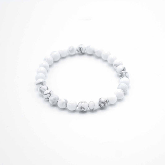A white howlite bead bracelet rests on a white surface.