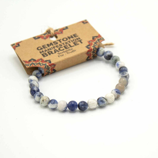 A beaded bracelet rests on a white background. The bracelet is made of sodalite gemstone beads and is packaged with a tag reading "GEMSTONE MANIFESTATION BRACELET Sodalite For: Truth".