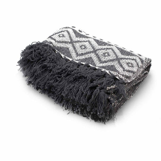 A black and white patterned throw blanket with a dark gray fringe rests on a white surface.