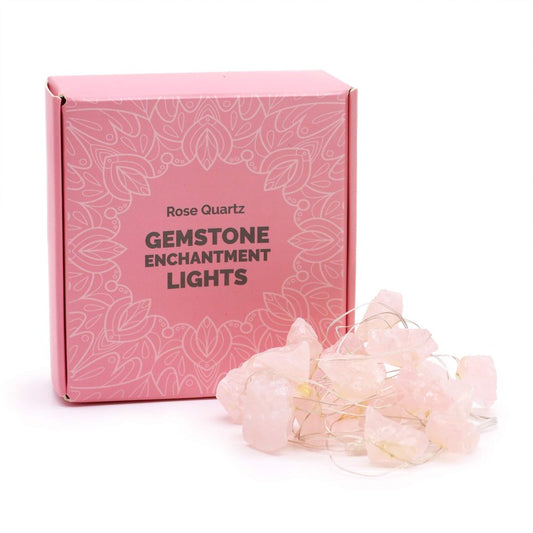 A pink box displaying "Rose Quartz GEMSTONE ENCHANTMENT LIGHTS" sits behind a pile of Rose Quartz Gemstone lights. The setting is a white surface.